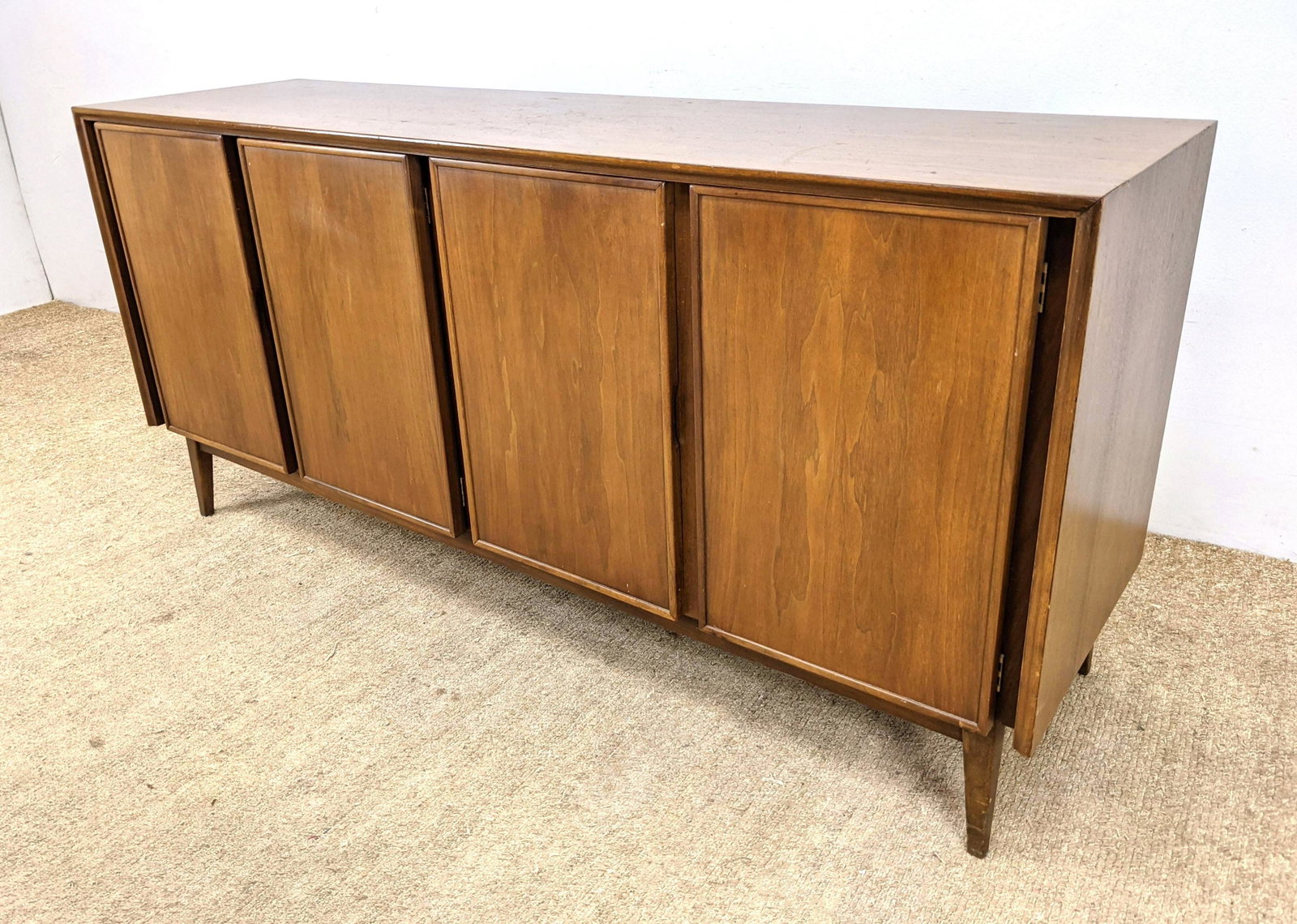 AMERICAN of MARTINSVILLE Modernist Walnut Credenza. Rai: AMERICAN of MARTINSVILLE Modernist Walnut Credenza. Raised on tapered legs. Marked. -- Dimensions: H: 30 inches: W: 64 inches: D: 18 inches ---