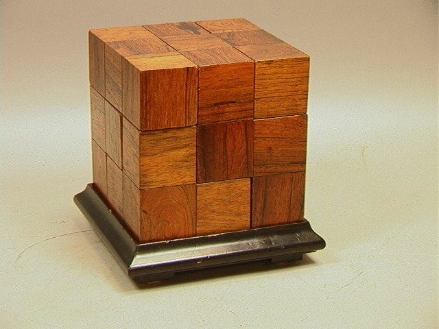 Modernist Wood Puzzle Table Sculpture. Joined RO: Modernist Wood Puzzle Table Sculpture. Joined ROSEWOOD Cubes can be arranged to create various forms. Sits on black ebonized base. 7 rosewood puzzle pieces.-- Dimensions: H: 8.5 inches: W: 7.5 inches 