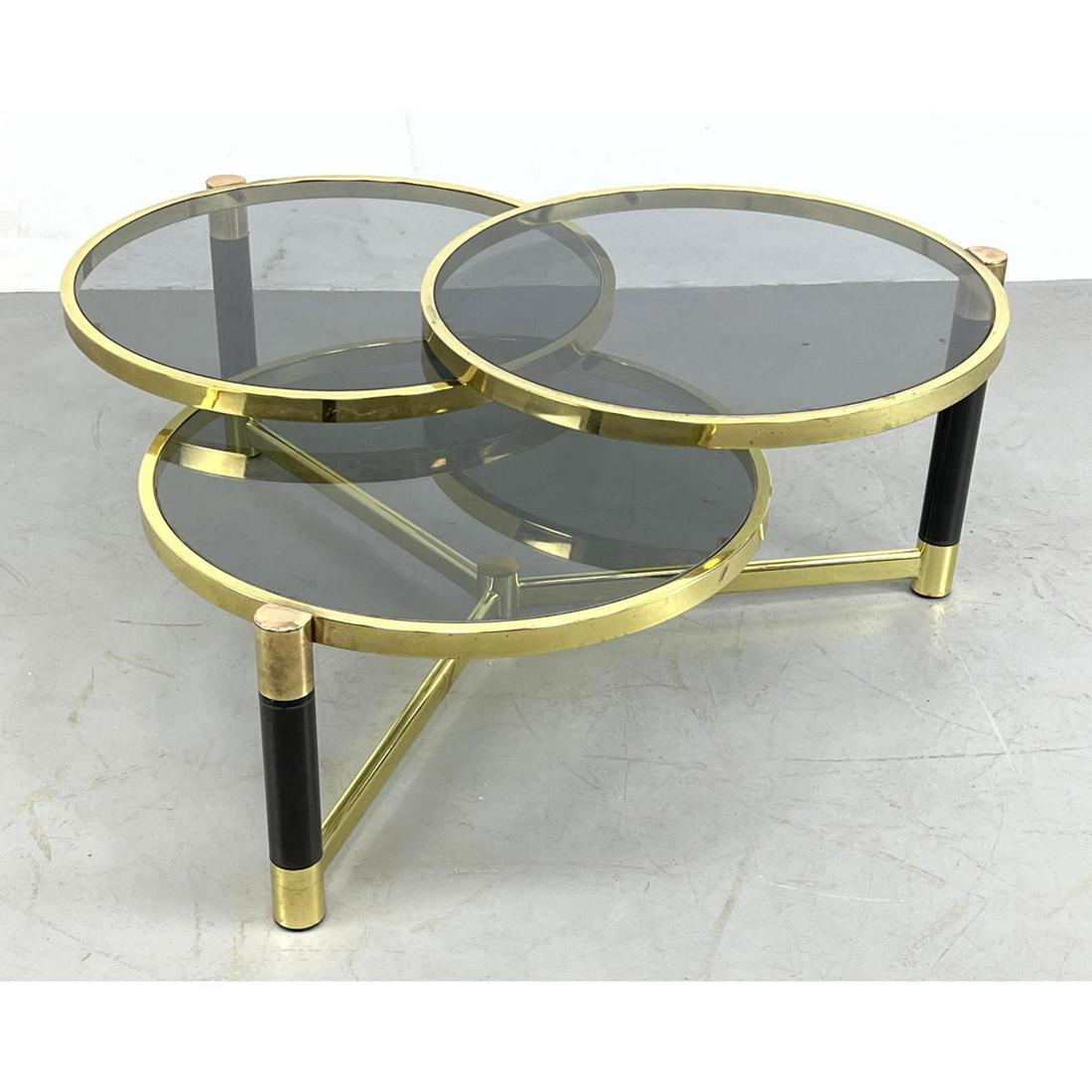 Karl Springer Style Tri Level Swing Arm Coffee Table. G: Karl Springer Style Tri Level Swing Arm Coffee Table. Gun metal and brass. Topaz Glass Dimensions: H: 17.5 inches: W: 42 inches: D: 42 inches ---