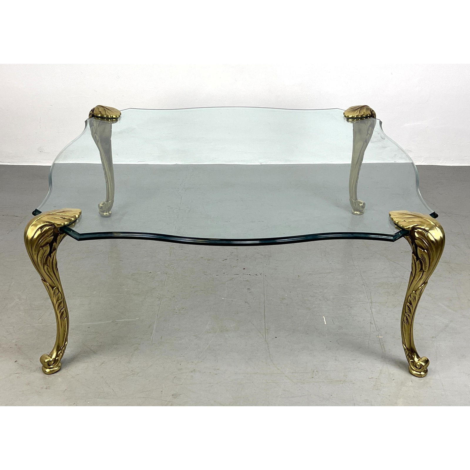 P.E. Guerin style Brass Leg Glass Top Coffee Table. Solid brass legs. Shaped glass top supported by (1 of 9)