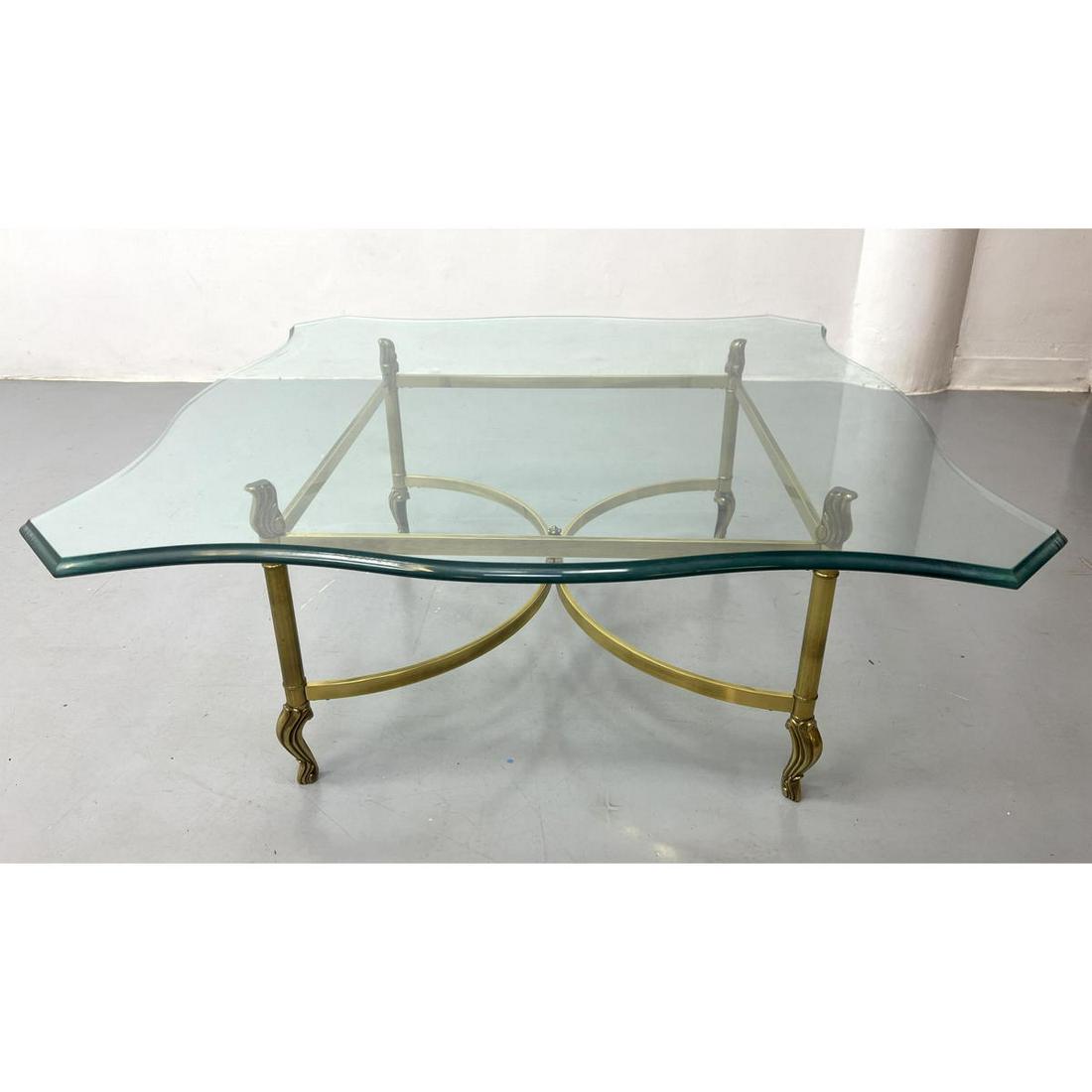 Brass and Glass Regency style Coffee Table. Bowed Brass Stretcher Base supports Shaped Glass Top.: Brass and Glass Regency style Coffee Table. Bowed Brass Stretcher Base supports Shaped Glass Top. Dimensions: H: 17 inches: W: 39.5 inches: D: 39.5 inches --- We offer curbside delivery to NYC, Manhat