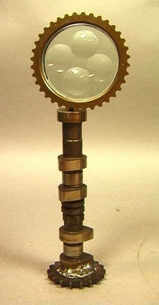 14" Industrial Table Sculpture bearing Signature: 14" Industrial Table Sculpture bearing Signature FELICIANO BEJAR. Round glass discs in brass cog wheel supported by crank shaft base. -- Dimensions: H: 14 inches: W: 4.75 inches --- US Shipping charge