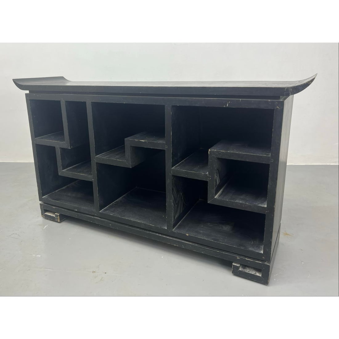 Ebonized Asian inspired Display Cabinet. Different shaped areas for display of decorative objects. T: Ebonized Asian inspired Display Cabinet. Different shaped areas for display of decorative objects. Top has flared side edges. Dimensions: H: 31 inches: W: 54 inches: D: 14 inches ---