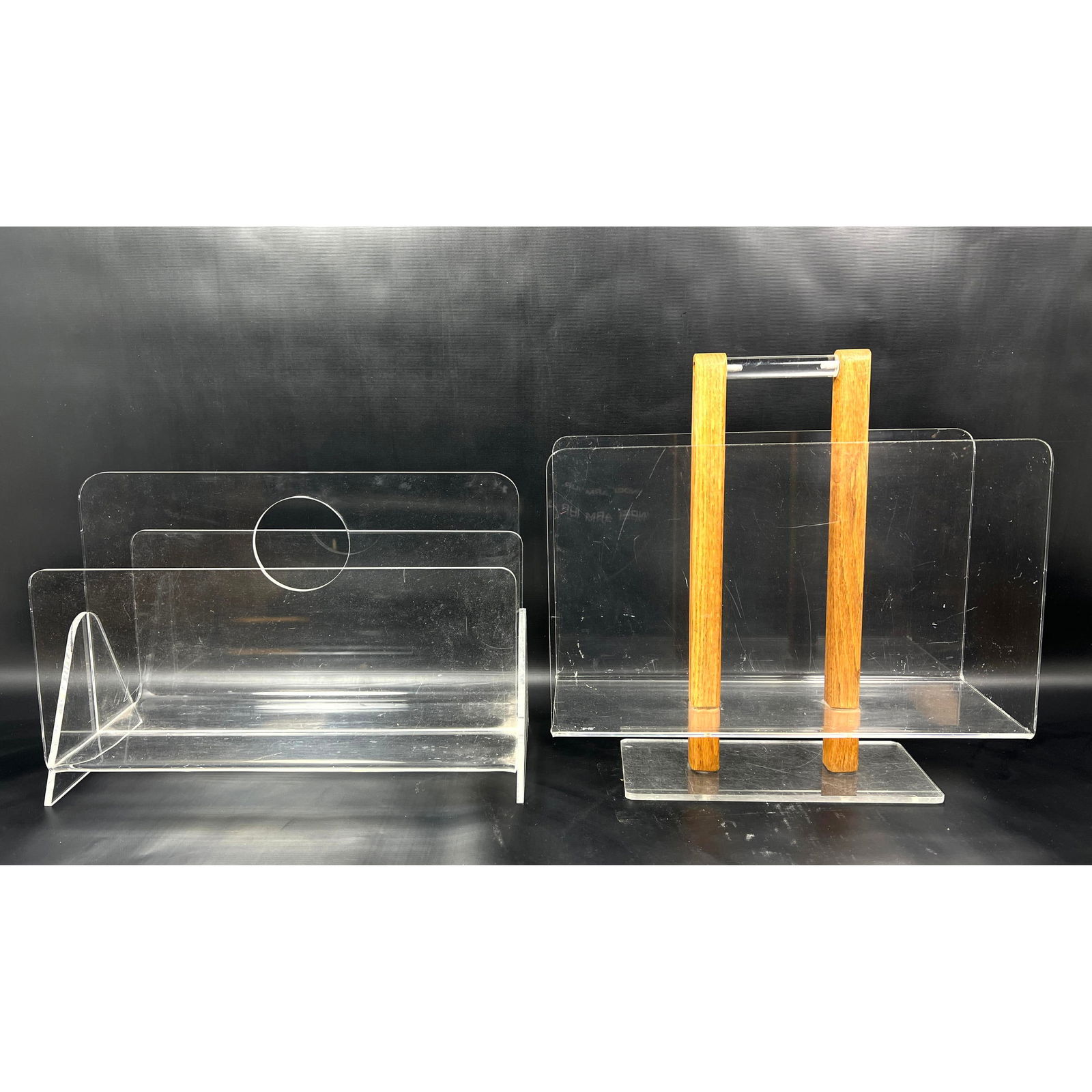 2pc Modernist Lucite Magazine Racks. One has central wood column handle.: 2pc Modernist Lucite Magazine Racks. One has central wood column handle. Dimensions: Height: 16 inches, Width: 16 inches, Depth: 6 inches. ---