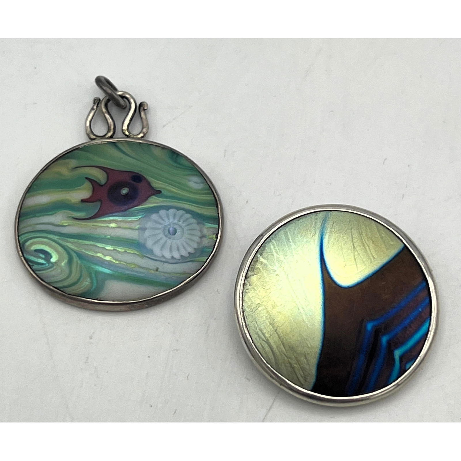 2pc Sterling Art Glass Pendants. LUNDBERG. CORREIA Studio. Fish Design. Feathered Wave Design. Both: 2pc Sterling Art Glass Pendants. LUNDBERG. CORREIA Studio. Fish Design. Feathered Wave Design. Both Marked. Dimensions: Height: 1.5 inches, Width: 1.25 inches. --- US Packing and Shipping charge: Jewe