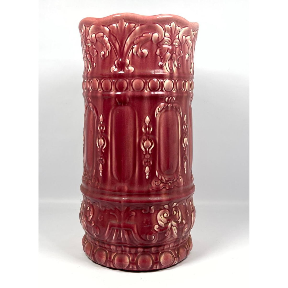 Rose glazed art pottery umbrella stand. Bearded head and floral scroll designs.: Rose glazed art pottery umbrella stand. Bearded head and floral scroll designs. Dimensions: Height: 20.5 inches, Width: 10.5 inches, Depth: 10.5 inches. ---