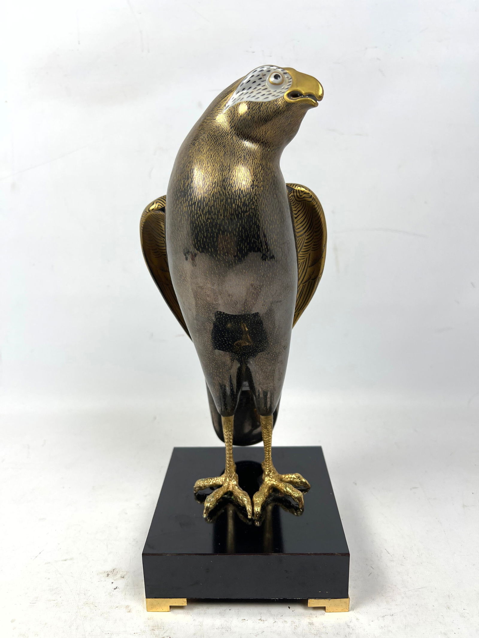 Oggetti Mangani Porcelain Falcon Sculpture. Label. Gold painted details. Metal legs.: Oggetti Mangani Porcelain Falcon Sculpture. Label. Gold painted details. Metal legs. Dimensions: Height: 12 inches, Width: 4.75 inches, Depth: 4.75 inches. --- US Packing and Shipping charge: In house