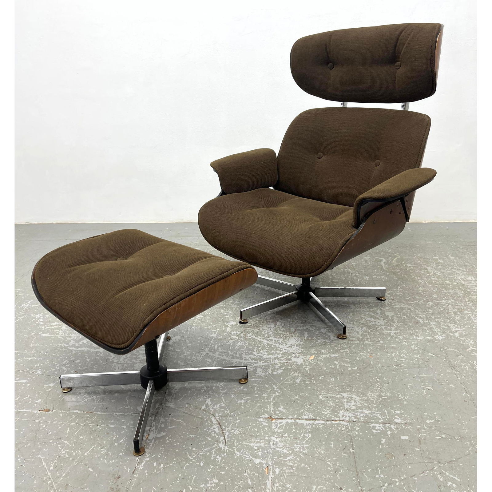 2pc SELIG Eames style Lounge Chair, Ottoman. Dark wood Shell frame with tufted fabric upholstery. Fa: 2pc SELIG Eames style Lounge Chair, Ottoman. Dark wood Shell frame with tufted fabric upholstery. Fabric SELIG label. Dimensions: Height: 41 inches, Width: 33 inches, Depth: 27.5 inches. - Seat Height