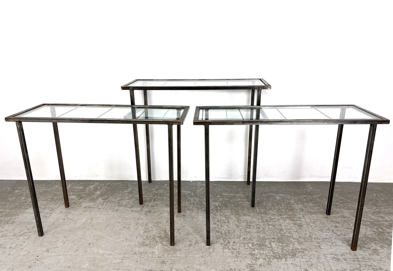 Set 3 Steel and Glass Console Display Tables. Inset Glass.: Set 3 Steel and Glass Console Display Tables. Inset Glass. Dimensions: Height: 38 inches, Width: 42 inches, Depth: 16 inches. - Additional Dimensions: 2 Smaller H: 33 inches, W: 42 inches, D: 16 inche