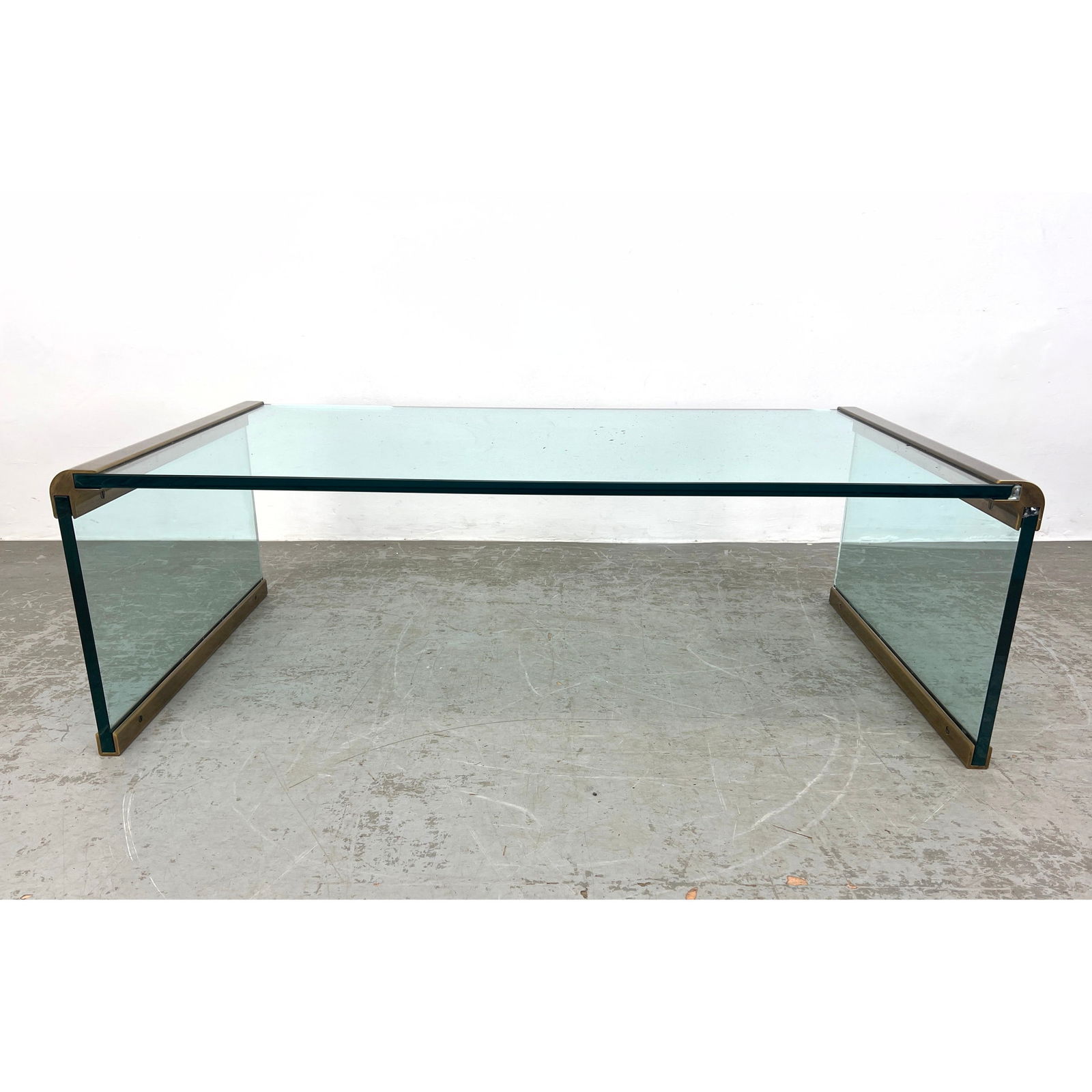 After Pace Glass Brass Trim Modernist Cocktail Table. Runners along bottom to protect glass.: After Pace Glass Brass Trim Modernist Cocktail Table. Runners along bottom to protect glass. Dimensions: Height: 16.5 inches, Width: 50 inches, Depth: 28 inches. --- - We offer curbside delivery for m