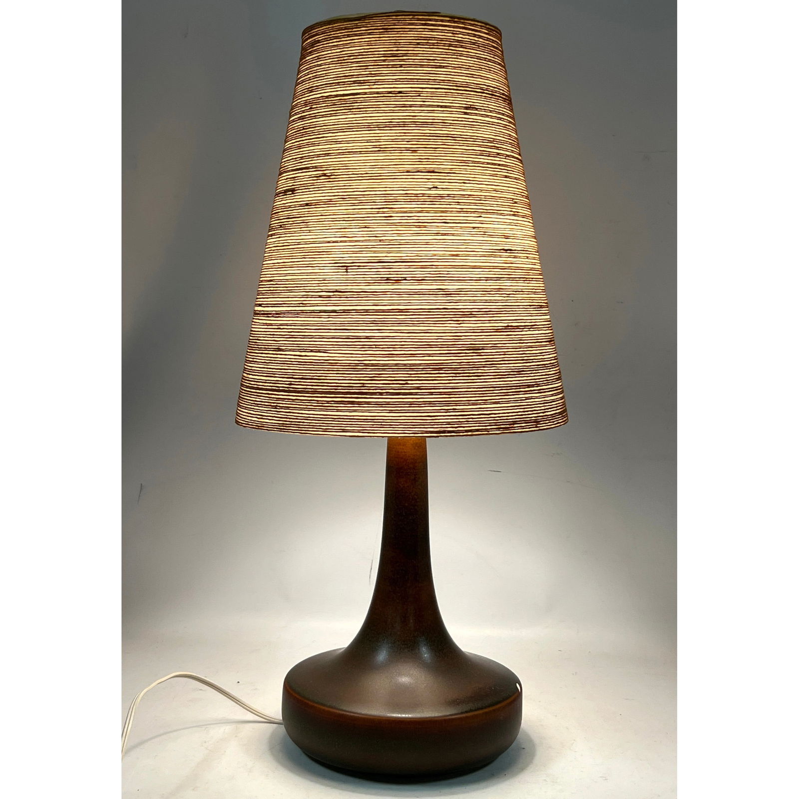Gunnar and Lotte Bostlund brown ceramic table lamp with original fiberglass and corded shade.: Gunnar and Lotte Bostlund brown ceramic table lamp with original fiberglass and corded shade. Dimensions: Height: 23.5 inches, Width: 10.5 inches, Depth: 10.5 inches. - Additional Dimensions: Pottery