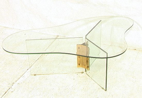 Freeform Glass Top Cocktail Coffee Table. 1/2" th: Freeform Glass Top Cocktail Coffee Table. 1/2" thick beveled glass. Three glass panel base with brass mounts. -- Dimensions: H: 16 inches: W: 49 inches: D: 29 inches ---