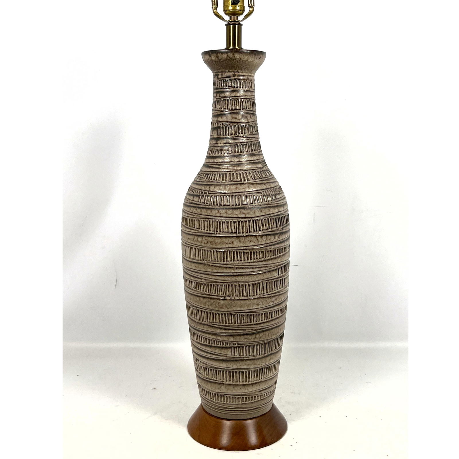 DESIGN TECHNICS by LEE ROSEN Carved Pottery Lamp. Tall MCM Ceramic Form with incised vertical ribbon: DESIGN TECHNICS by LEE ROSEN Carved Pottery Lamp. Tall MCM Ceramic Form with incised vertical ribbon bands. Walnut Base Rim. Unsigned. Dimensions: Height: 36 inches, Width: 9 inches, Depth: 9 inches.