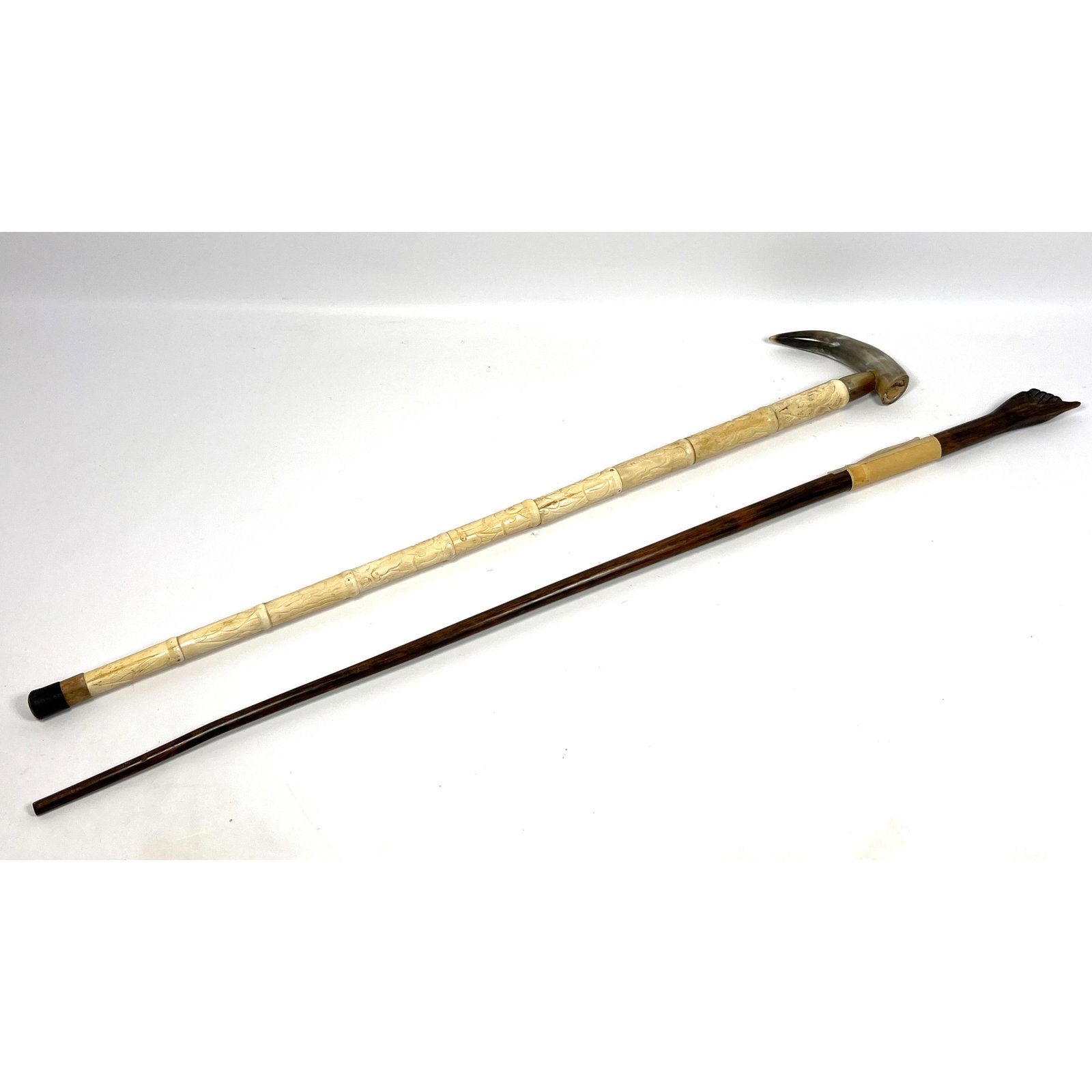2pcs Canes Walking Sticks. The first is a dark, polished wooden walking stick, featuring a hand-ca: 2pcs Canes Walking Sticks. The first is a dark, polished wooden walking stick, featuring a hand-carved handle in the form of an upward-pointing hand An aged paper label affixed to the shaft is inscrib