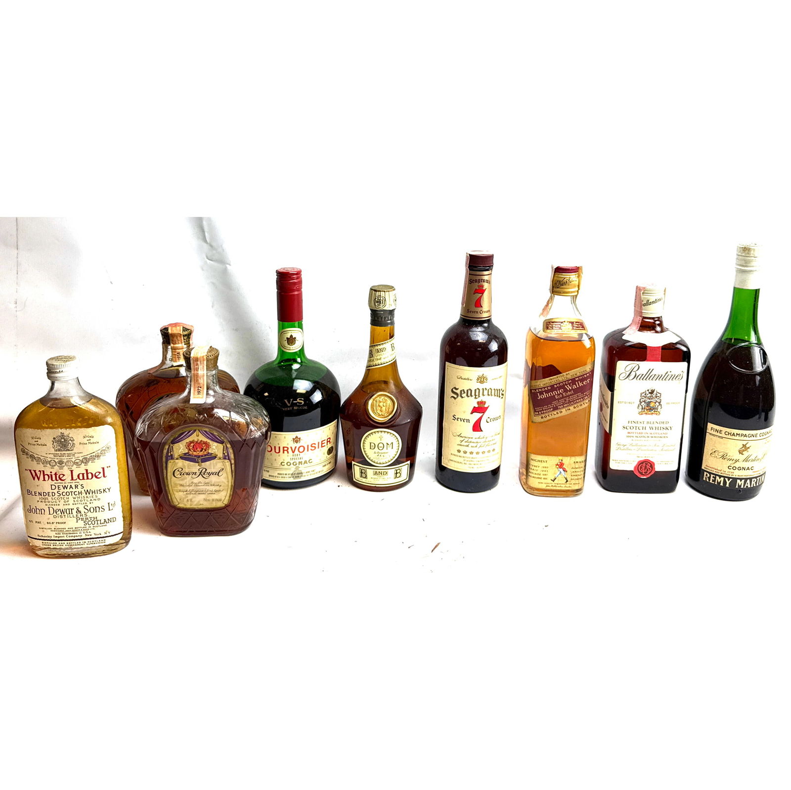 9 Bottle Whisky. Johnny Walker red Label, Ballantines Scotch whiskey, Remy Martin, DOM, Courvoisier,: 9 Bottle Whisky. Johnny Walker red Label, Ballantines Scotch whiskey, Remy Martin, DOM, Courvoisier, Seagrams, Royal Crown, Dewars White Label,Unopened. Dimensions: Height: 12 inches, Width: 4 inches,