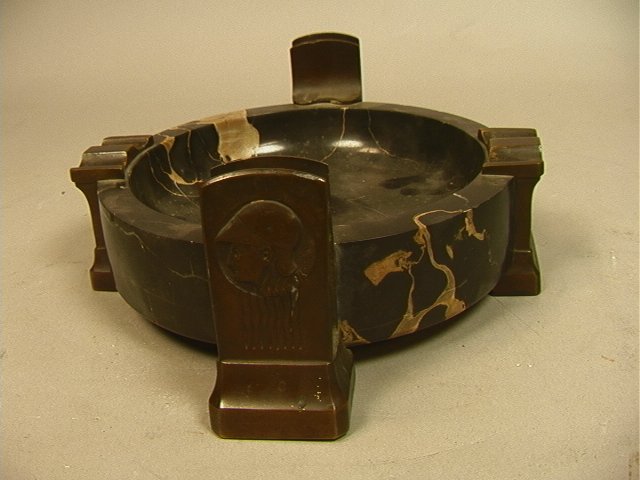 Austrian Secessionist Bronze Marble Cigar Ashtray: Austrian Secessionist Bronze Marble Cigar Ashtray. Round Black Marble Ashtray with Four Bronze Mounts. Match Holders Decorated with heads with helmets. Other mounts have Floral bouquets. -- Dimensions
