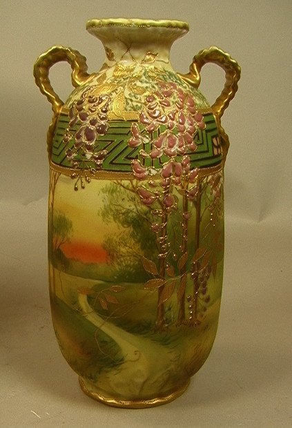 NIPPON Hand Painted Porcelain Ribbon Handled Vase: NIPPON Hand Painted Porcelain Ribbon Handled Vase. Scenic Sunset & Landscape Decoration with Raised Enamel Painted WISTERIA FLOWERS. Raised gilt paint trim & decoration. Marked. -- Dimensions: H: 11 i