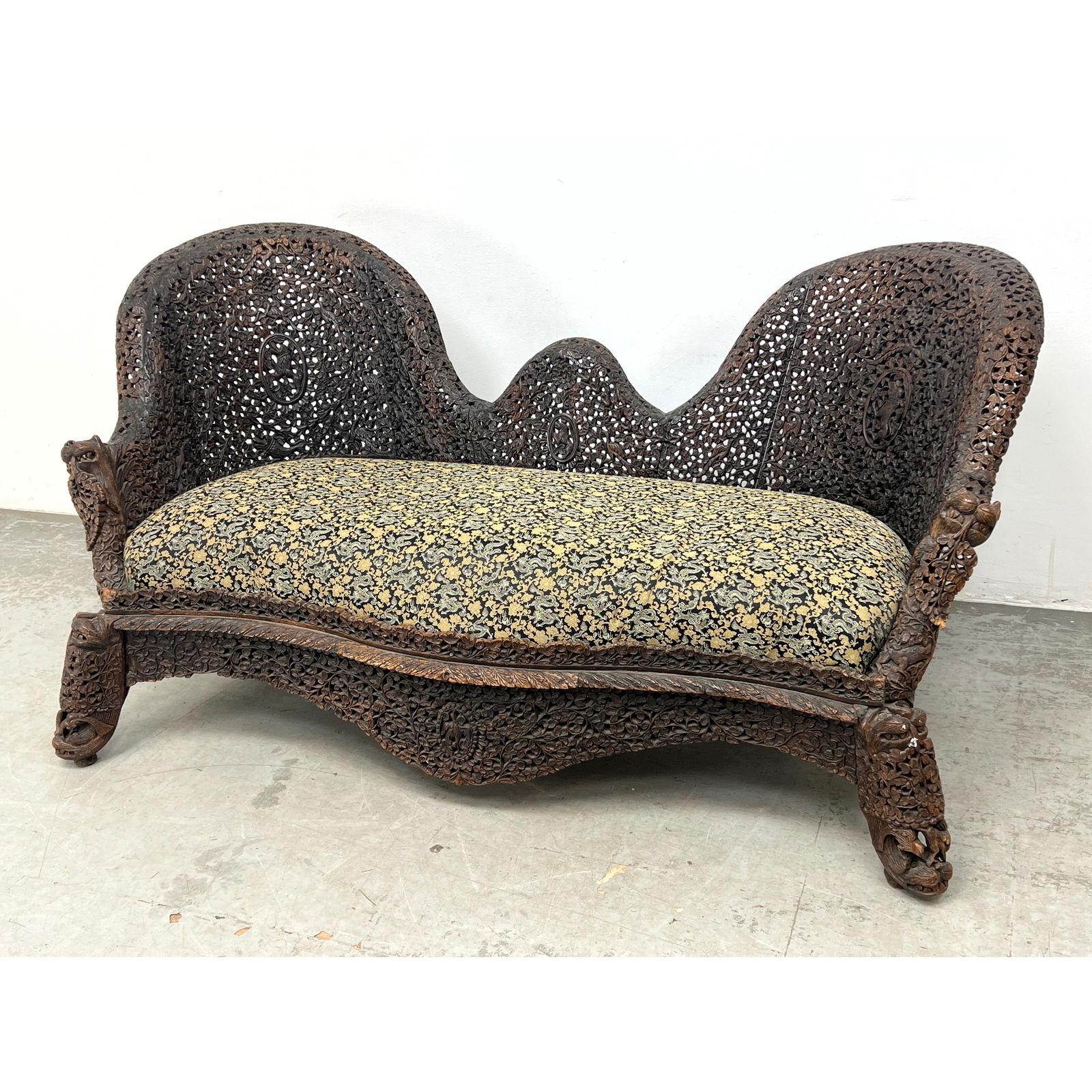 Antique Anglo-Indian settee constructed from a dark-stained hardwood, featuring extensive pierced fo: Antique Anglo-Indian settee constructed from a dark-stained hardwood, featuring extensive pierced foliate and floral carving throughout the frame. BURMESE Dimensions: Height: 34 inches, Width: 69