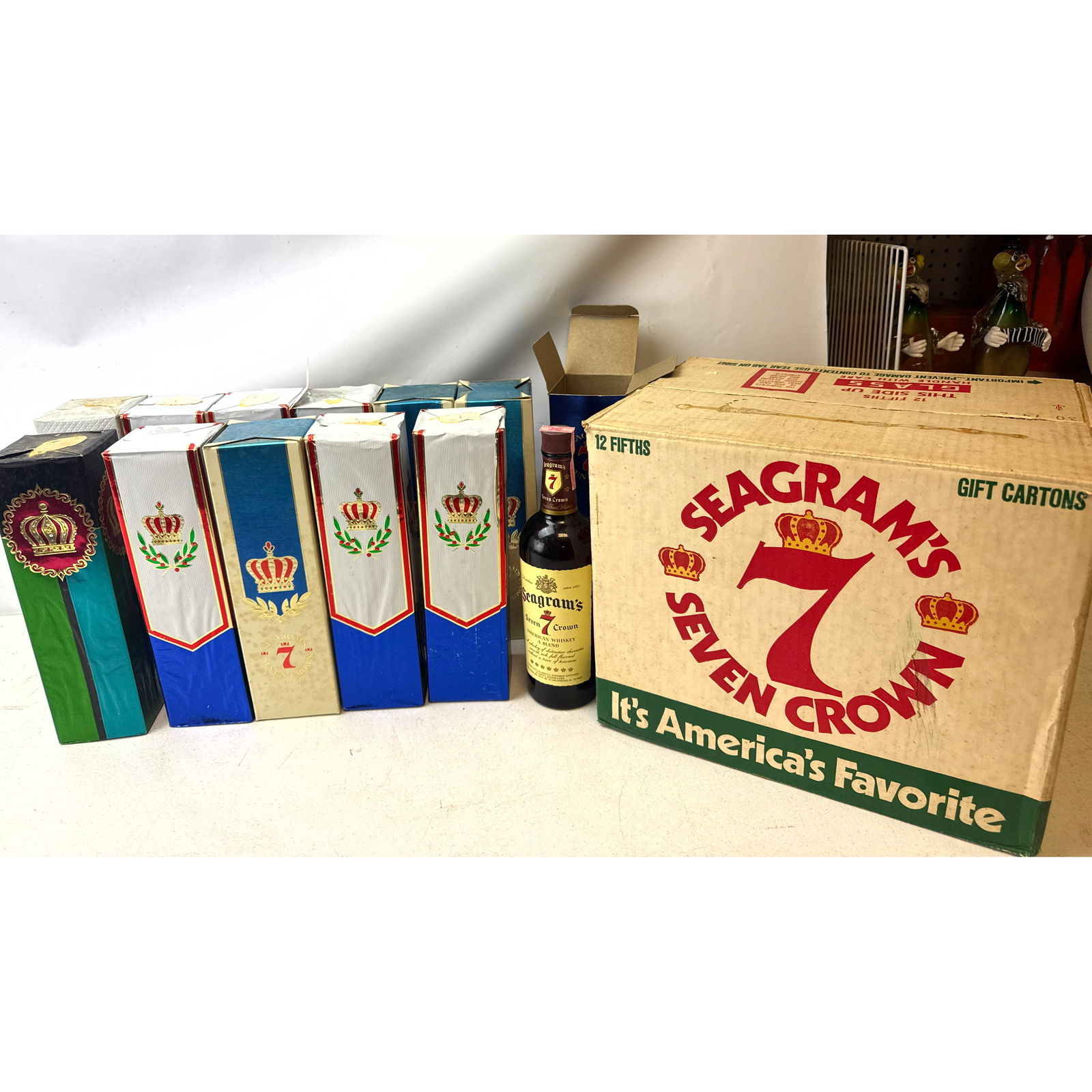 12 fifths of Seagrams 7 Crown Whiskey in vintage foil gift wrapping. Different vintages. 12 unopened: 12 fifths of Seagrams 7 Crown Whiskey in vintage foil gift wrapping. Different vintages. 12 unopened units. With original 1970s era case box. Dimensions: Height: 12 inches, Width: 3 inches,