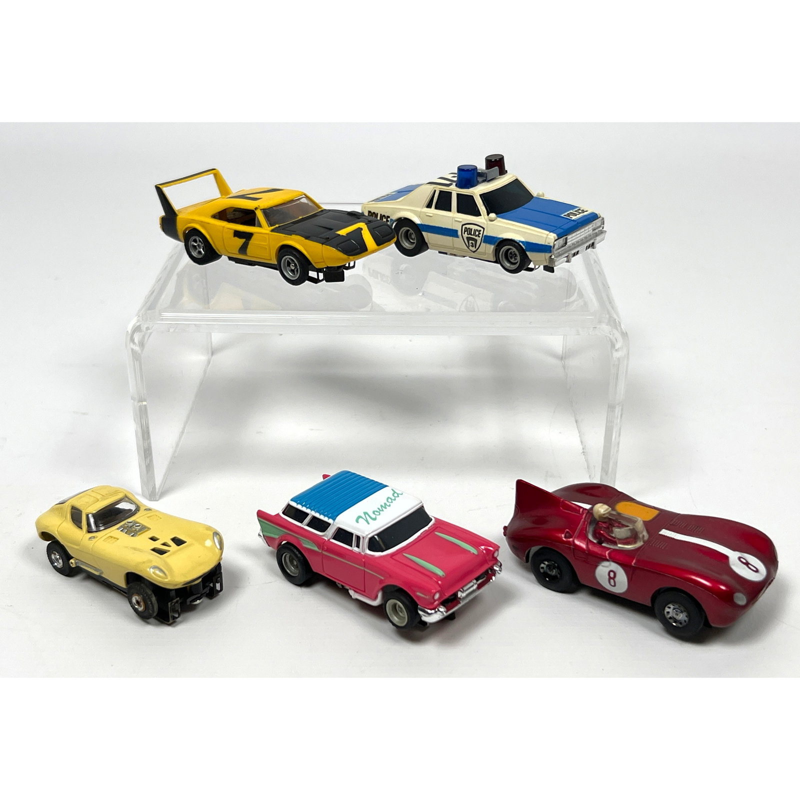 5 vintage HO scale slot cars manufactured by Aurora and Tyco. The group features three Aurora A/FX m: 5 vintage HO scale slot cars manufactured by Aurora and Tyco. The group features three Aurora A/FX models including a four-door police cruiser in cream and blue with a blue and red light bar, a 1969 D
