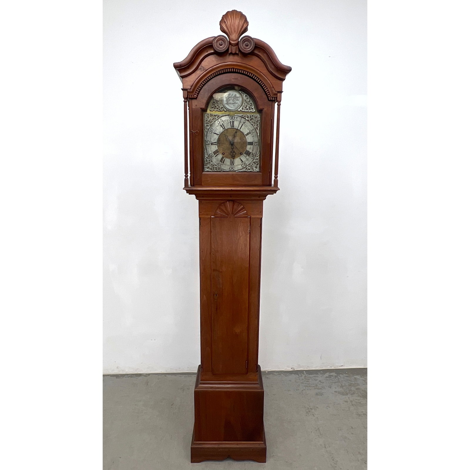 18th-century tall case clock by Rudy Stoner of Lancaster, Pennsylvania. The case is constructed of h: 18th-century tall case clock by Rudy Stoner of Lancaster, Pennsylvania. The case is constructed of hardwood featuring a broken-arch pediment with carved rosettes and a central shell-carved finial.