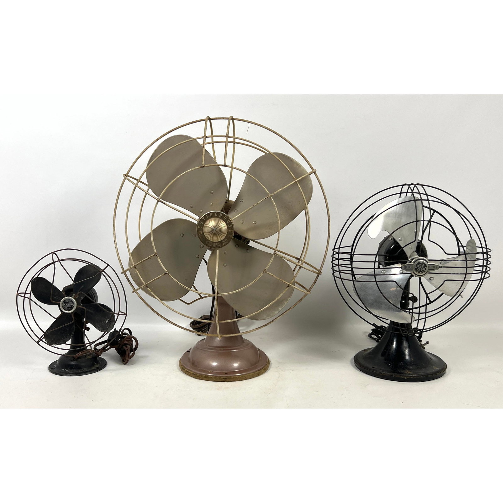 3pcs Vintage Fans. The largest unit is a Westinghouse model 16SD4, finished in a metallic tan paint.: 3pcs Vintage Fans. The largest unit is a Westinghouse model 16SD4, finished in a metallic tan paint. It features a four-blade metal design protected by a wire cage and is mounted on a teardrop-shaped
