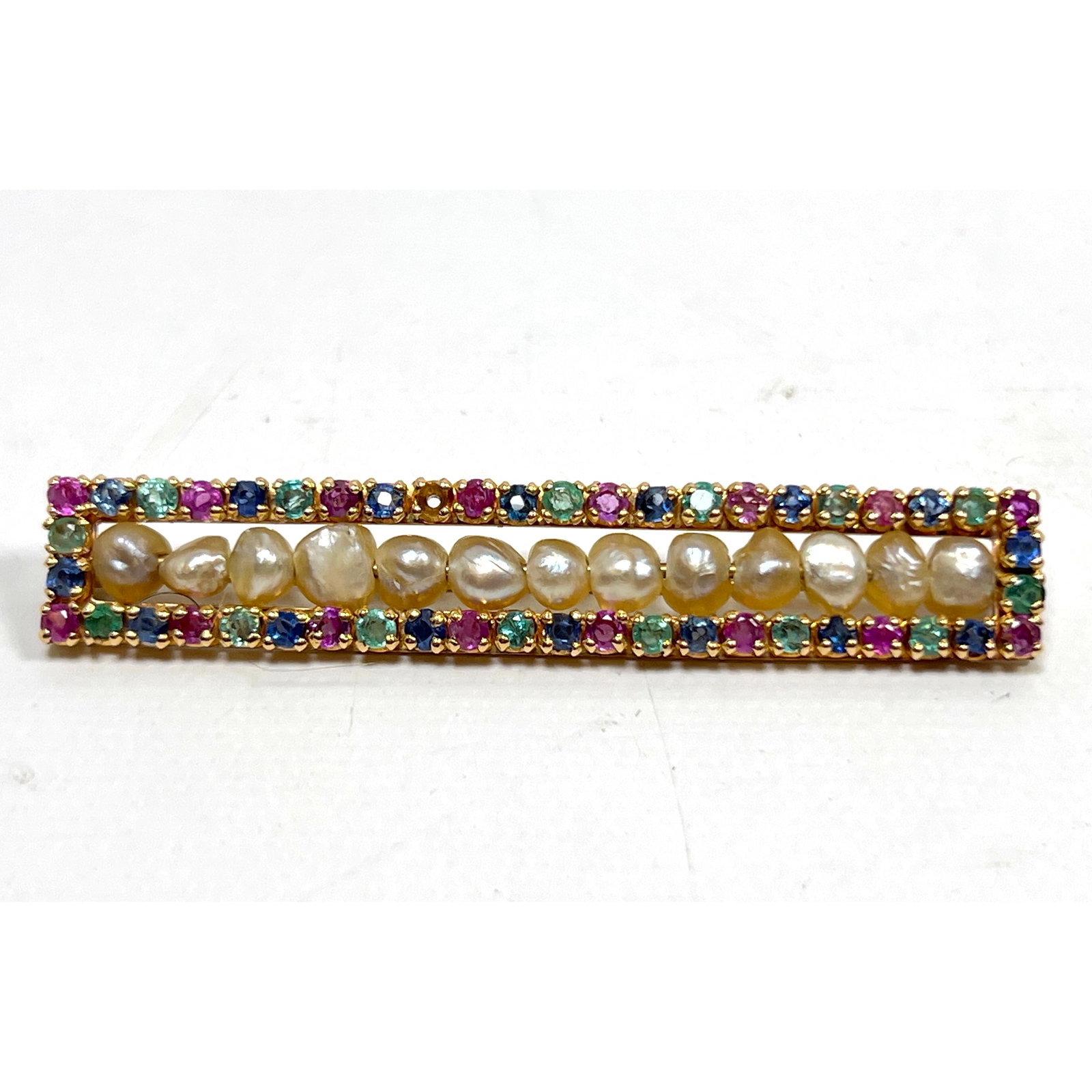 14K Gold Antique Bar Pin. Slim Rectangular Frame has Rubies, Emeralds and Sapphires framing irregula: 14K Gold Antique Bar Pin. Slim Rectangular Frame has Rubies, Emeralds and Sapphires framing irregular pearls. Unmarked. Tests 14k. Dimensions: Height: .5 inches, Width: 2.75 inches, Depth: .25 inches.