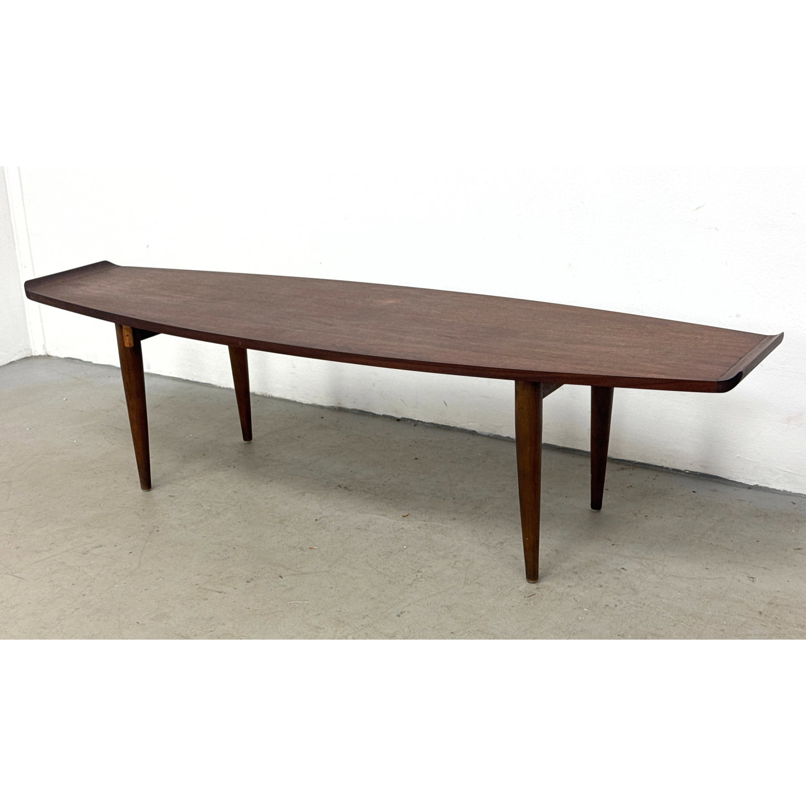 Mid-Century Modern Walnut Surfboard Coffee Table. Sculpted Upturned Ends and Tapered Legs Dated Apri: Mid-Century Modern Walnut Surfboard Coffee Table. Sculpted Upturned Ends and Tapered Legs Dated April 1962 Dimensions: Height: 15.5 inches, Width: 60 inches, Depth: 18 inches. ---