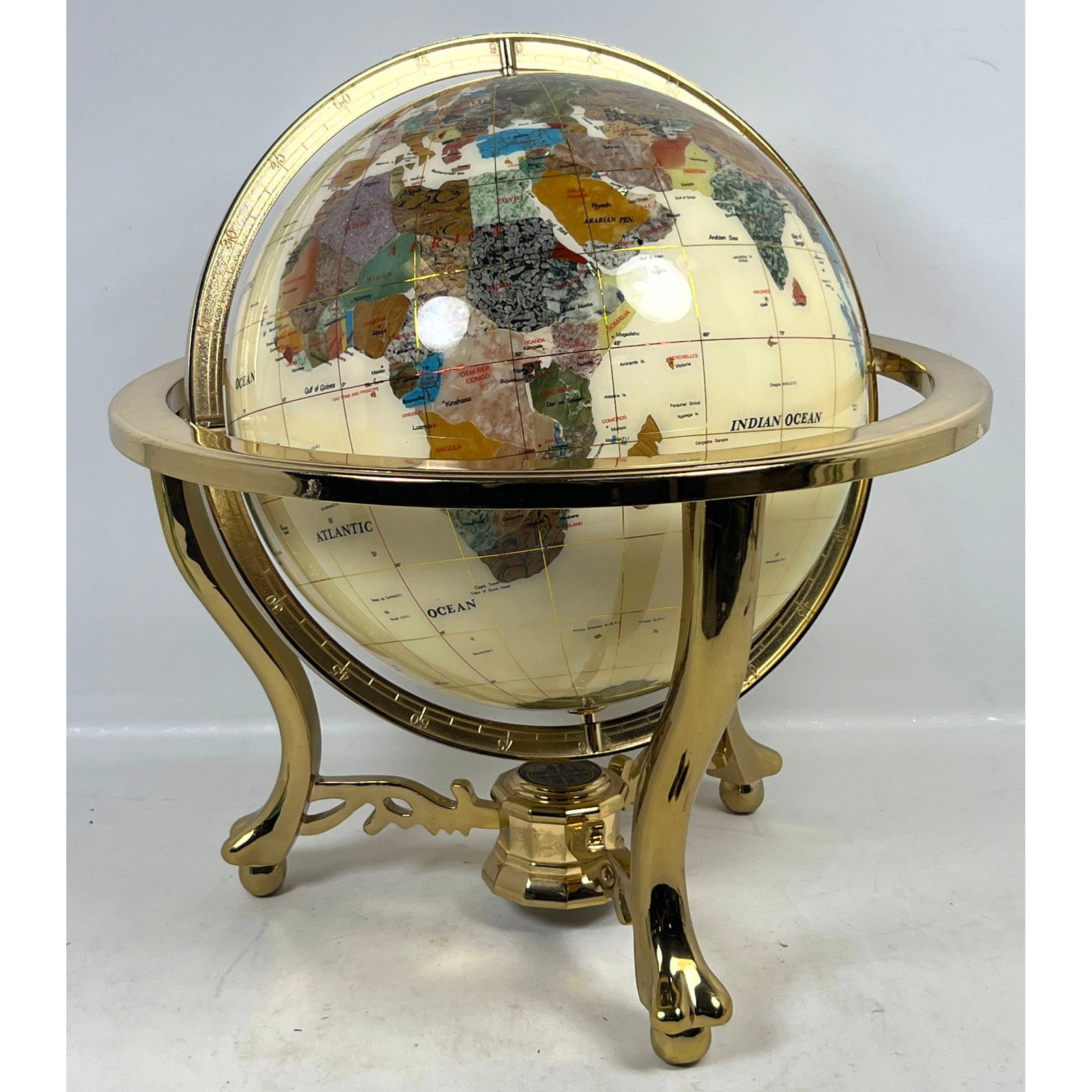 Tabletop Mother of Pearl and Semi-Precious Gemstone Globe Mounted in a Gold Toned Metal Compass Base: Tabletop Mother of Pearl and Semi-Precious Gemstone Globe Mounted in a Gold Toned Metal Compass Base Dimensions: Height: 19 inches, Width: 18 inches, Depth: 18 inches. ---