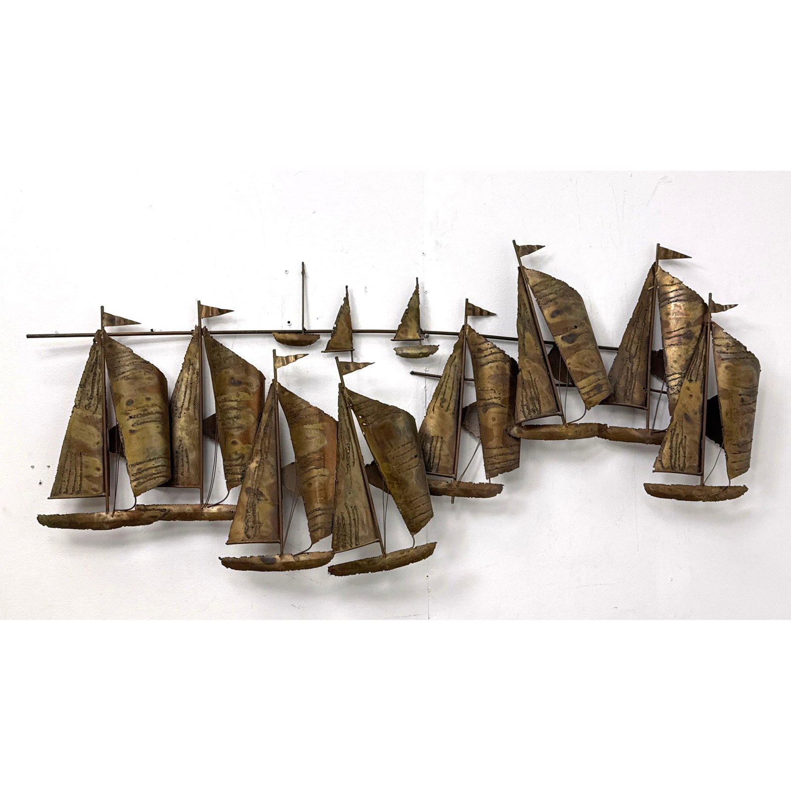 Brutalist Metal Sailboat Regatta Wall Sculpture in the style of Curtis Jere with torch cut sails and: Brutalist Metal Sailboat Regatta Wall Sculpture in the style of Curtis Jere with torch cut sails and variegated patina. Unsigned. Dimensions: Height: 21.5 inches, Width: 49 inches, Depth: 3 inches. --