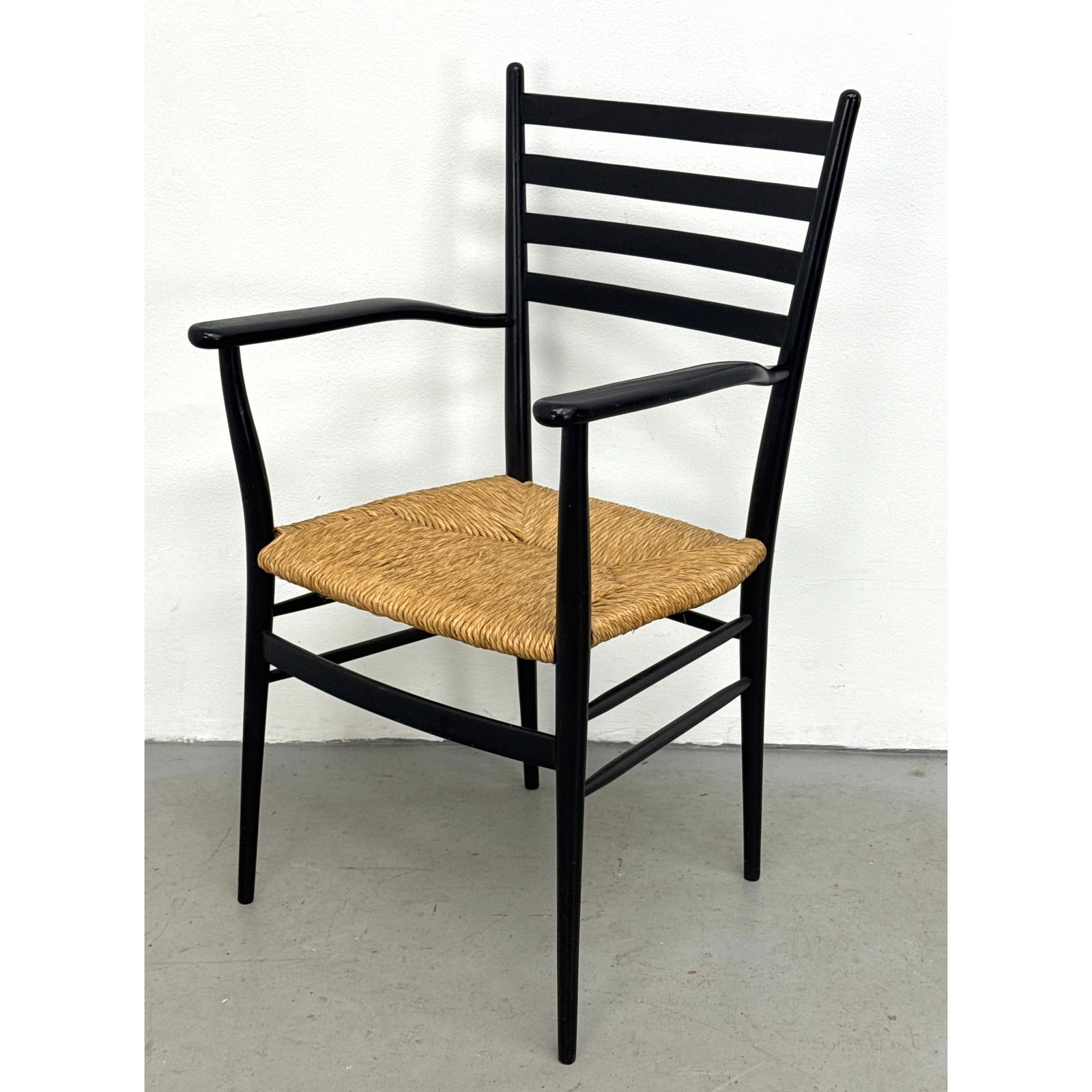 Italian Mid-Century Modern Ladderback Armchair in the Style of Gio Ponti with Black Painted Frame an: Italian Mid-Century Modern Ladderback Armchair in the Style of Gio Ponti with Black Painted Frame and Woven Rush Seat. Unsigned. Dimensions: Height: 37 inches, Width: 21 inches, Depth: 20 inches. - Se