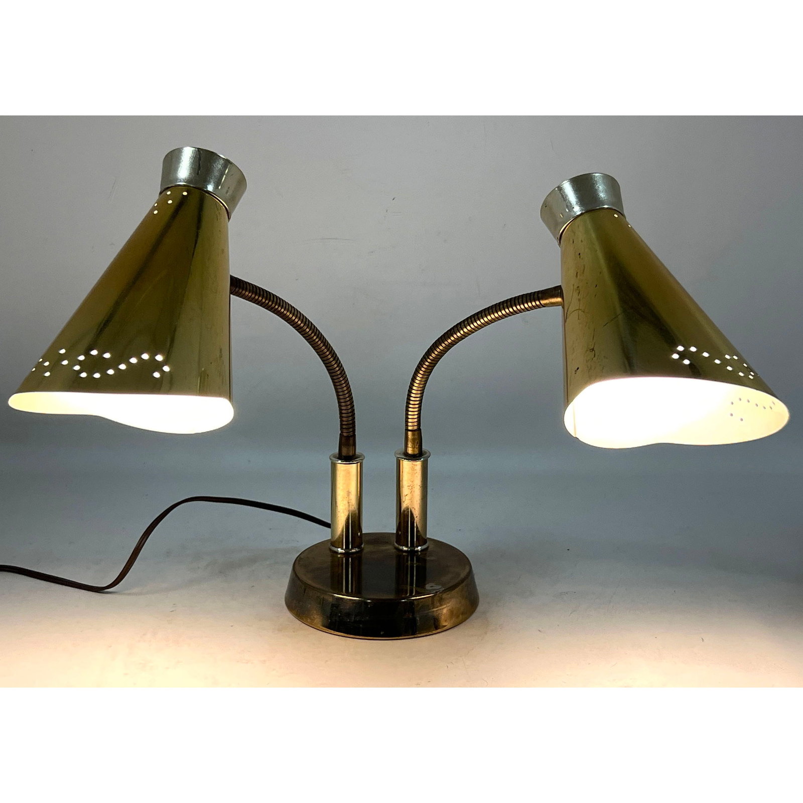 Mid-Century Modern double gooseneck brass plated desk lamp with conical pierced shades and dual rota: Mid-Century Modern double gooseneck brass plated desk lamp with conical pierced shades and dual rotary switches. Dimensions: Height: 18.5 inches, Width: 10 inches, Depth: 5.5 inches. --- US Packing
