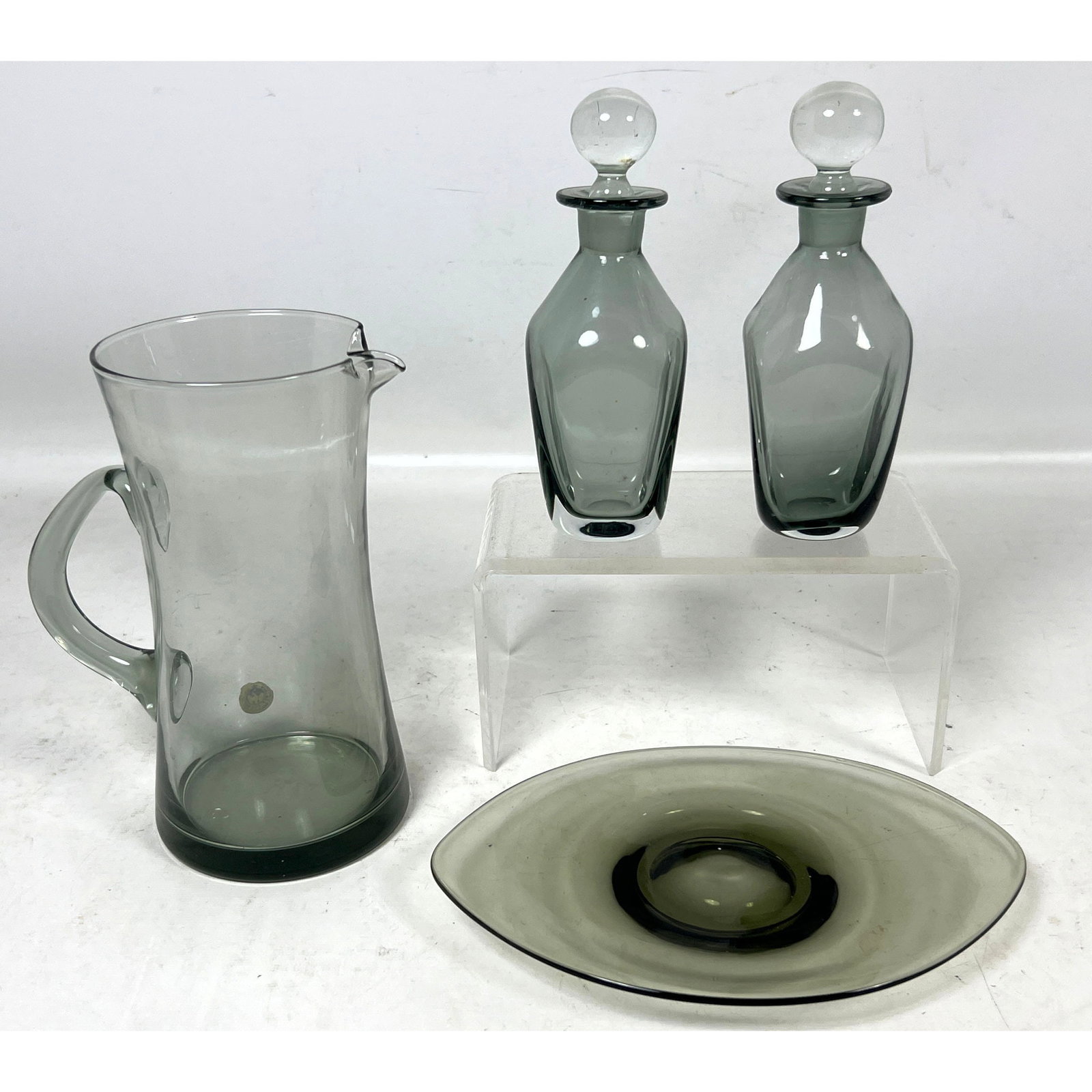 4pc set of Kastrup Holmegaard smoke gray art glass including a pitcher two decanters and an oval pla: 4pc set of Kastrup Holmegaard smoke gray art glass including a pitcher two decanters and an oval plate Dimensions: Height: 7.5 inches, Width: 6 inches, Depth: 4 inches. --- US Packing and Shipping cha