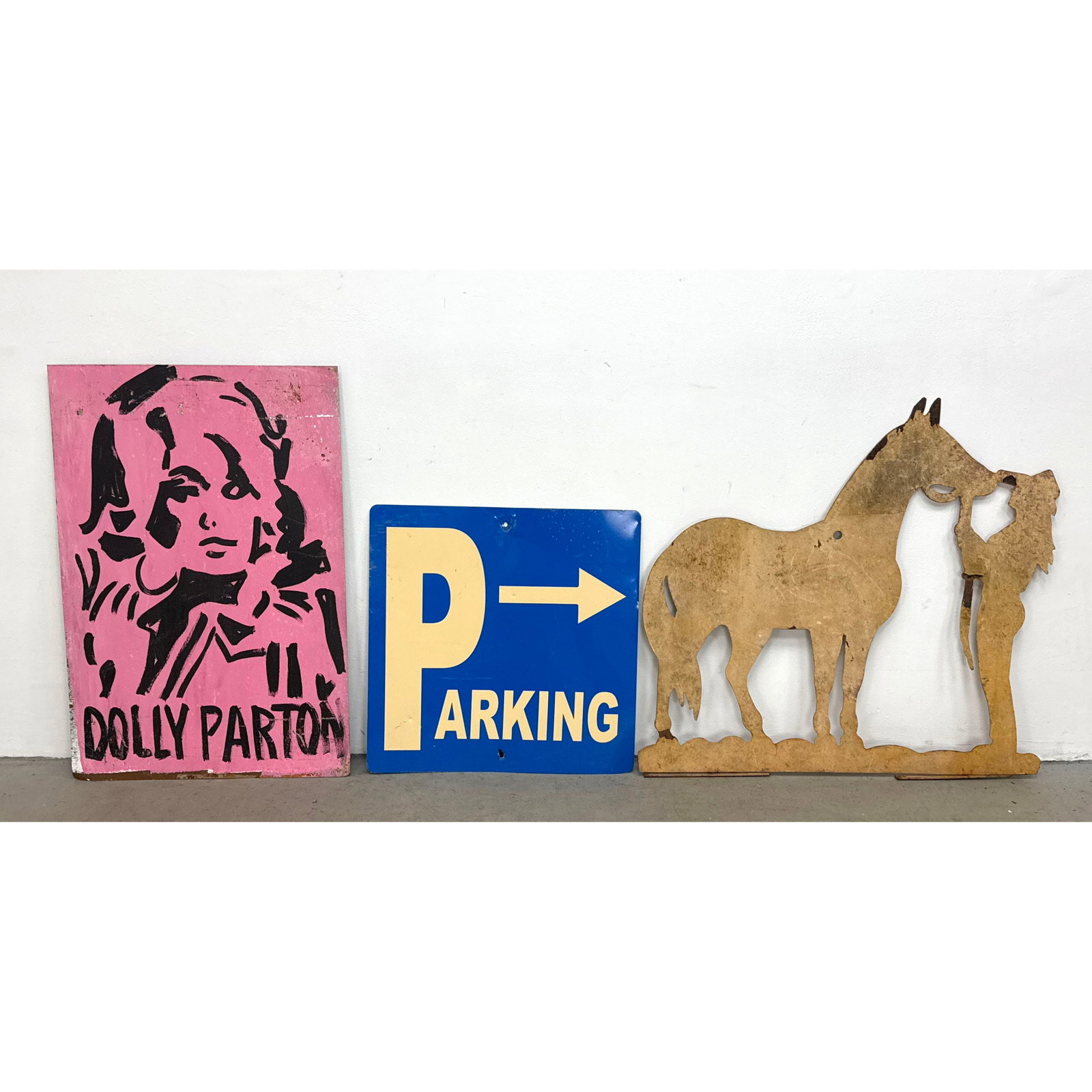 3pc Hand painted Dolly Parton portrait on plywood, blue metal directional Parking sign, and rusted m: 3pc Hand painted Dolly Parton portrait on plywood, blue metal directional Parking sign, and rusted metal horse and cowgirl silhouette display Dimensions: Height: 36 inches, Width: 24 inches. ---