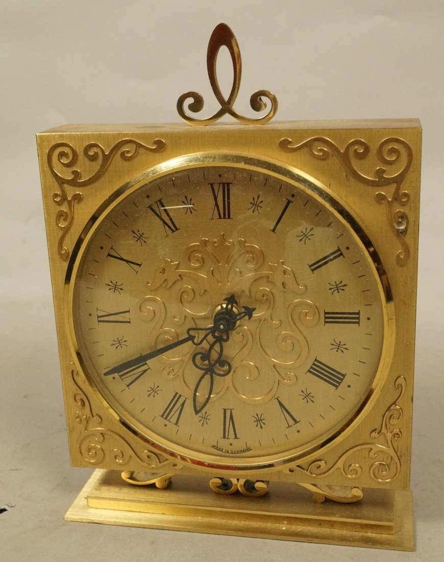 German Made Desk Clock. Gold Tone Metal Clock.: German Made Desk Clock. Gold Tone Metal Clock. Fancy applied decoration. Battery op.-- Dimensions: H: 8 inches: W: 6 inches: D: 2.25 inches --- US Shipping charge: $20