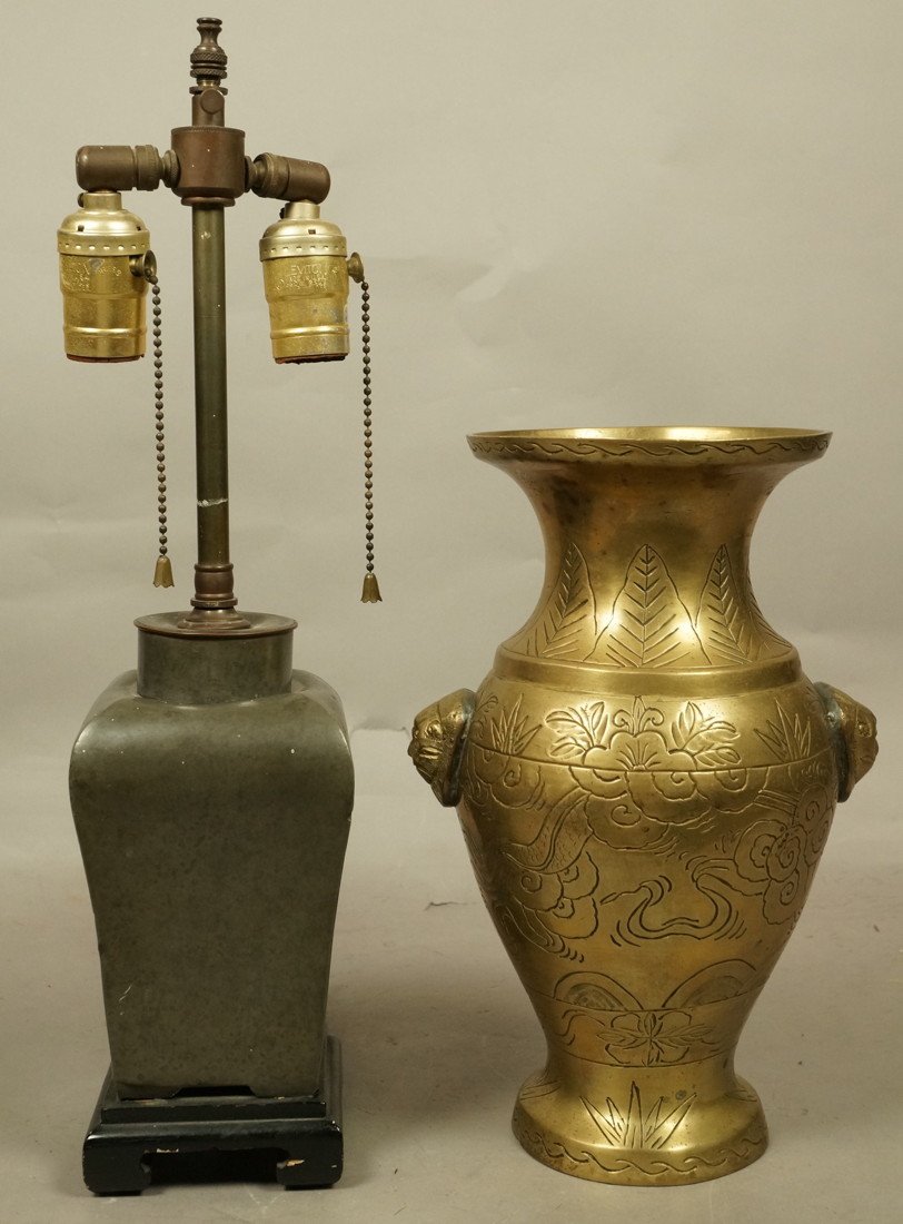 2pc Asian Metal Lot. 1). Pewter Urn Table Lamp. C: 2pc Asian Metal Lot. 1). Pewter Urn Table Lamp. Carved ebonized wood base. 2). Handled Brass Vase with animal handles. Incised with flora & cloud design.-- Dimensions: H: 18 inches: W: 4.25 inches ---