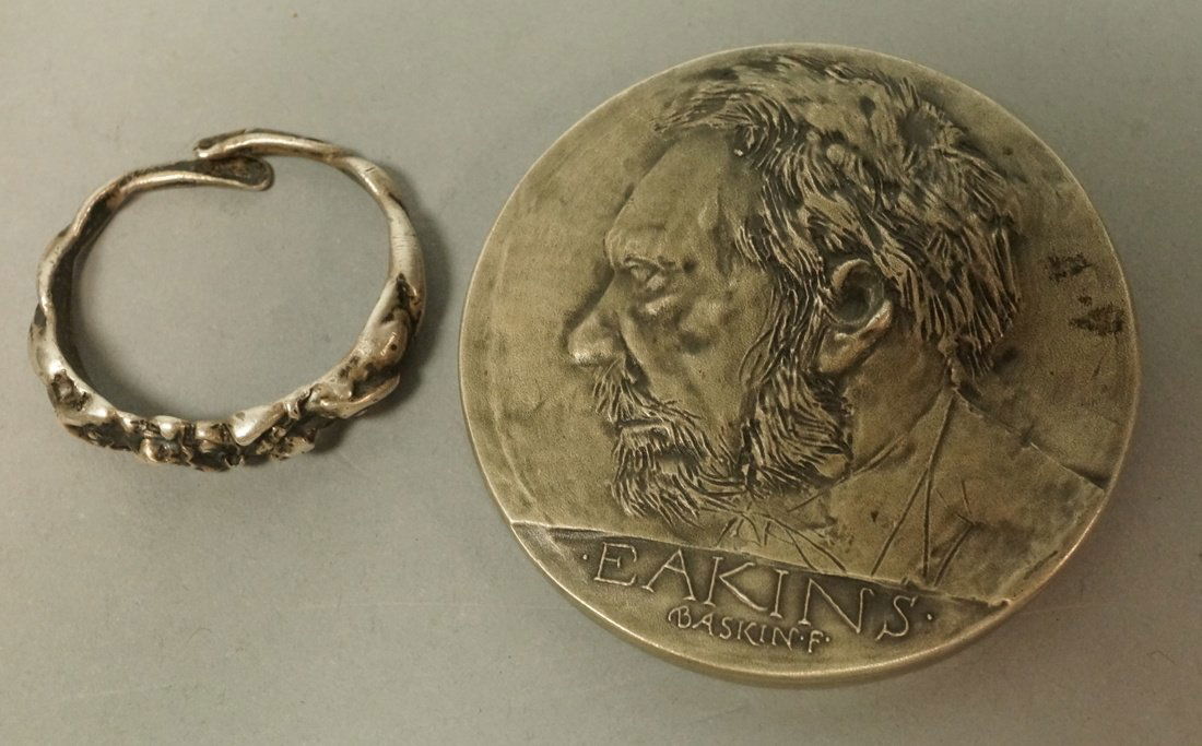 2pcs signed Sterling. 1) UNGER Brothers Nude Fema: 2pcs signed Sterling. 1) UNGER Brothers Nude Female circular form object. Marked. Small loop ring form with crossover ends. 2) (Thomas) EAKINS Sterling Medal Medallion. Dated 1972. Marked.-- Dimension