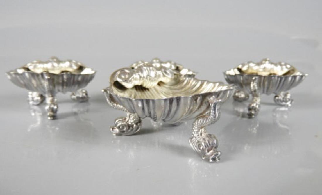 HMS SALTS WITH DOLPHIN FEET: A set of four hallmarked silver salts designed as a shell resting on dolphin shaped feet or legs, dated 1867, 380 grams.