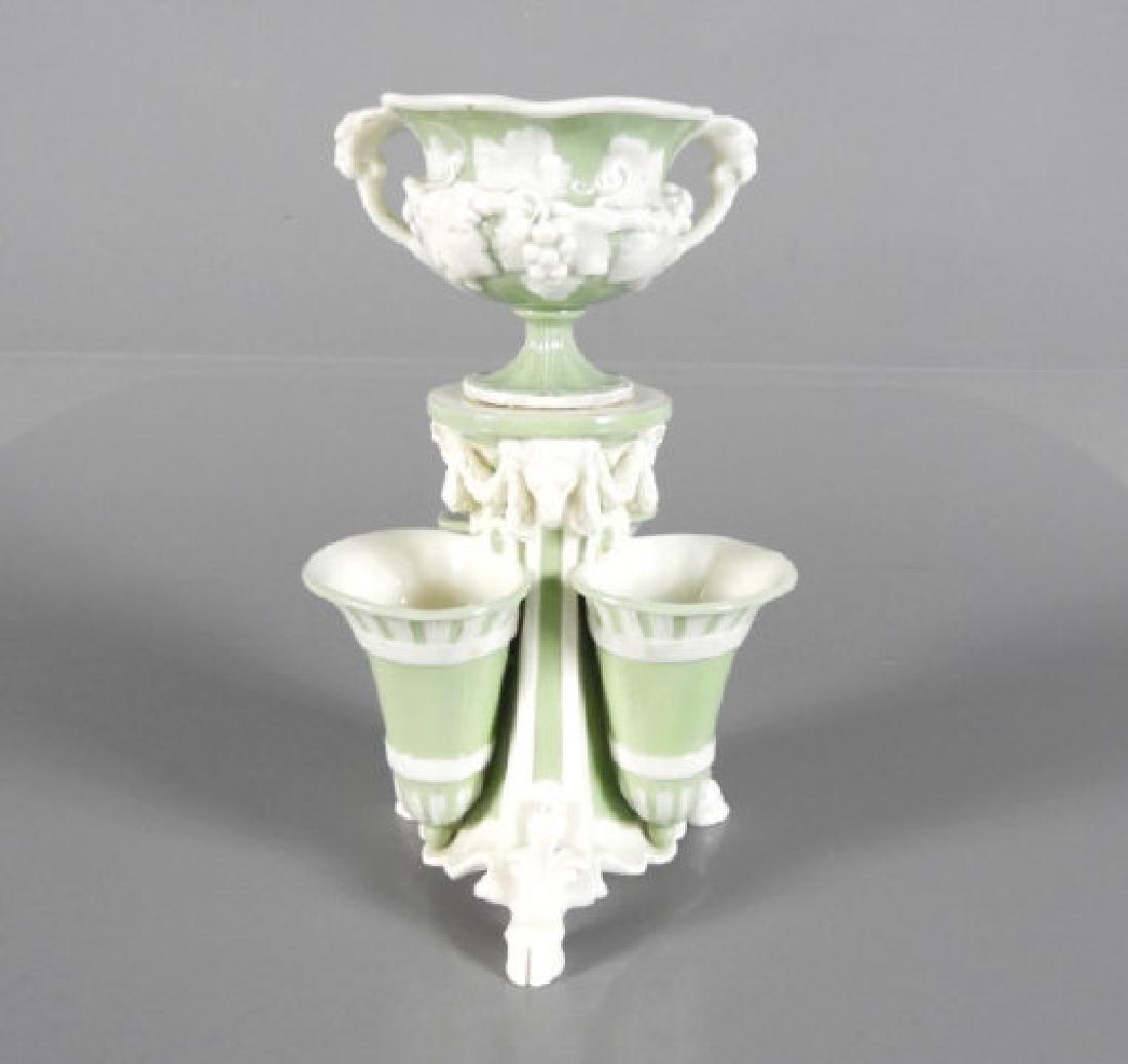 19TH CENTURY MINTON PATE-SUR-PATE VASE: A 19th Century Minton celadon pâte-sur-pâte two-tier vase, three pocket vases below a central urn, decorated with white rams' heads, swag and grape vines, on a celadon ground, resting on ram