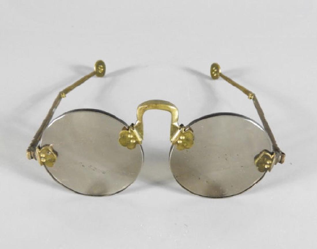 PAIR OF CHINESE REPUBLIC PERIOD SUNGLASSES: A pair of Chinese Republic period crystal sunglasses, round smoky lenses affixed to a bronze bridge, pierced folding arms, 2 1/4 x 5 1/2 x 6 inches.