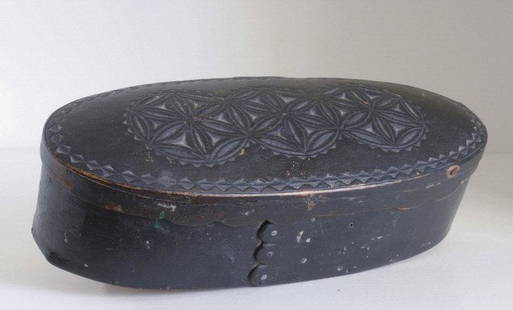 OVAL BIRCH BOX / BOÎTIER OVAL EN MERISIER, QUEBEC: A small elongated oval carved birch box in original black paint with three linked pinwheel geometric designs on the top and a scalloped edge to the overhanging domed lid. Quebec, early 19th 