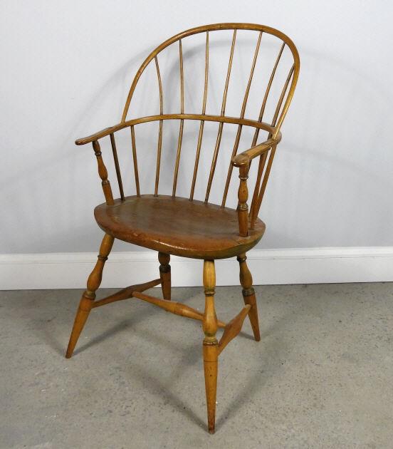 AMERICAN BOW-BACK WINDSOR CHAIR, CIRCA 1800: An 18th century American bow-back Windsor armchair, having a red stained white pine seat, elm armrests and spindles, raised on turned pipe-stem supports, remnants of mustard paint, restorations. North