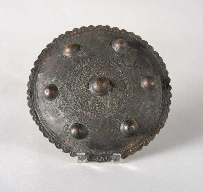 SUMATRAN PEURISE SHIELD: A Sumatran Peurise shield, originating from Aceh. Patinated brass, decorated with seven applied stars and inscribed decoration. Diameter, 9.5".