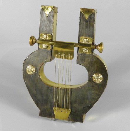 ANTIQUE MUSIC STORE ADVERTISING HARP: A brass and wood music store advertising sign. The harp shaped sign decorated with brass roundels, strings and brass trim. London, 19th Century. Dimensions, 17" x 13" x 2".