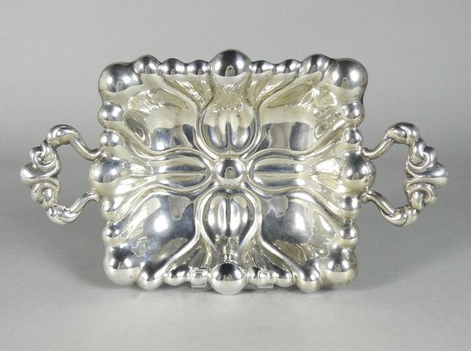 LINZ - SILVER BREAD TRAY, AUSTRIAN: An early 20th century Austrian silver bread tray, the lobed rectangular body with scrolled open handles, raised on foliate cast scrolled supports. Impressed marks for .800 silver, town marks for Linz 