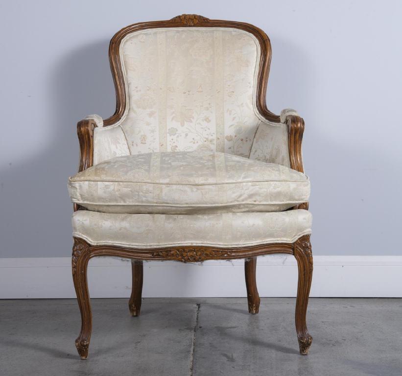 WALNUT FRAMED LOUIS XV STYLE BERGERES: A 20th century walnut framed bergere in the Louis XV style, showing a foliate carved crest rail and reeded hand grips, raised on cabriole supports. Dimensions, 37" high x 25" wide.