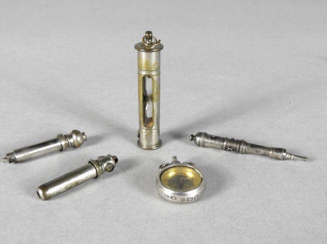 MECHANICAL PENCILS, HOURGLASS & SILVER COMPASS: An interesting mechanical pencil shaped like a cannon and two more fitted with Stanhope views. A 15-second hourglass timer along with a hallmarked silver compass marked for C. E. Williams, Birmingham.
