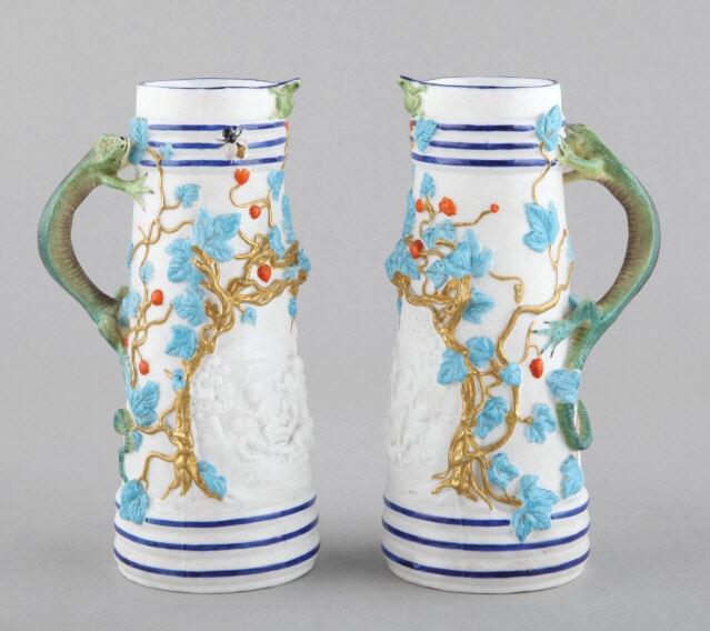 PAIR OF STAFFORDSHIRE EWERS: A pair of small cabinet ewers by George Jones, Staffordshire, with applied vines and berries, and lizard shaped handles. Marked to base. Dimensions, 6.5" h x 2.75" diameter.