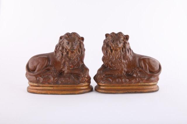 Imposing Pair of Chalkware Lions, Mid 19th Century: An imposing pair of chalkware lions in original brown and gold paint. Made in England in the mid 19th century, these would have graced a mantel in a country house. H: 10"; L: 11".