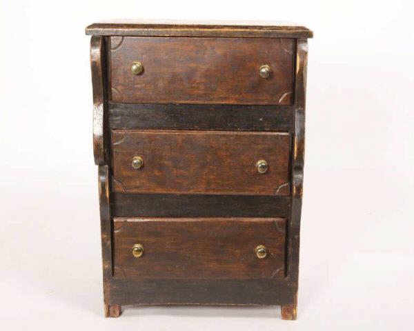 Empire Style Chest of Drawers, Québec, Circa 1875: A child's three-drawer Empire style chest of drawers in original brown paint with a bevel edge top and shaped front posts. Nailed construction, Quebec, circa 1875. H: 29"; W: 20"; D: 15". Collection: 
